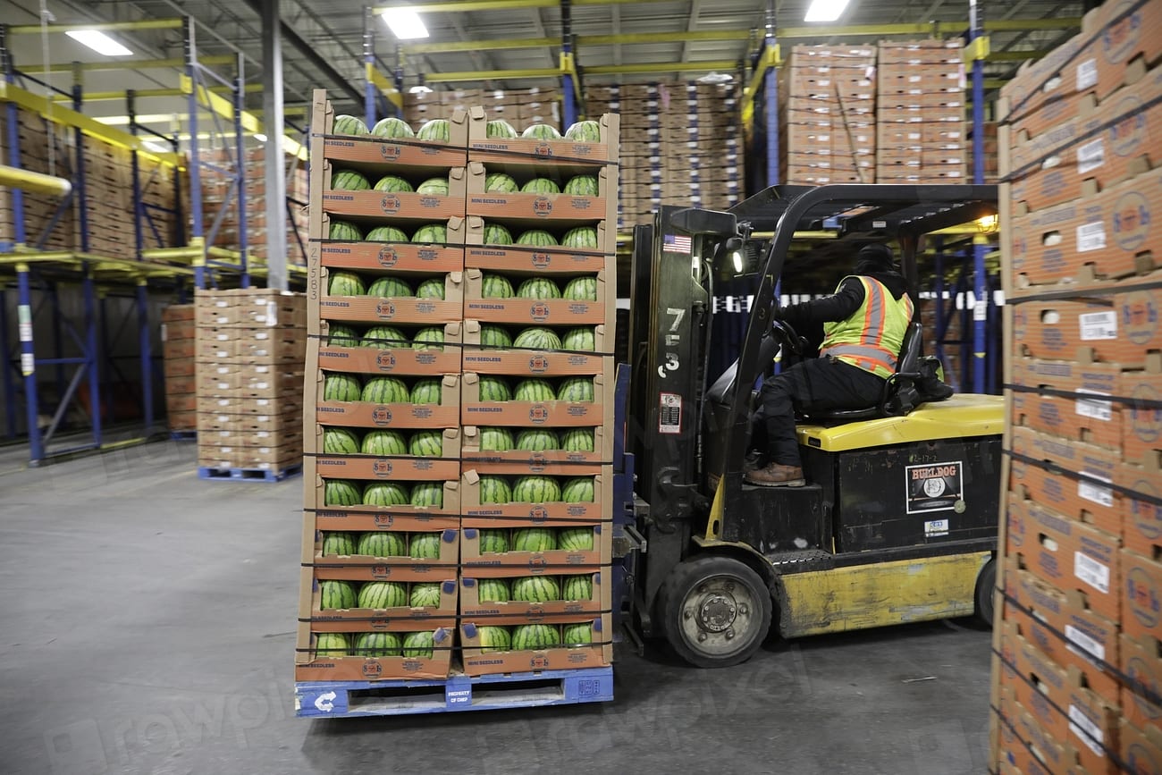 Empilhadeira levando um palete de caixas de melancia num centro de distribuição de alimentos